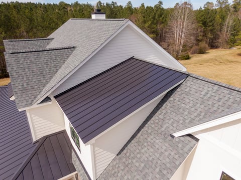 Modern farmhouse with asphalt and metal roofing under construction